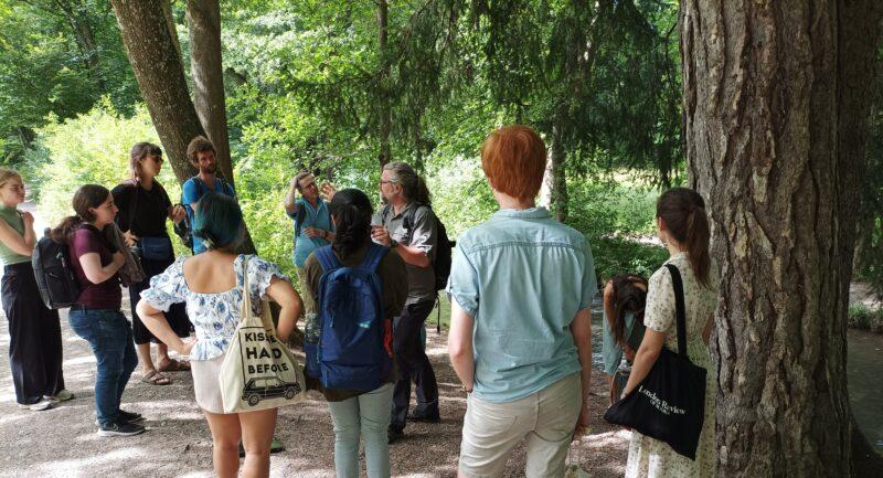 A group of students and Norbert Pantel standing nearby trees in the Augsburg city forest