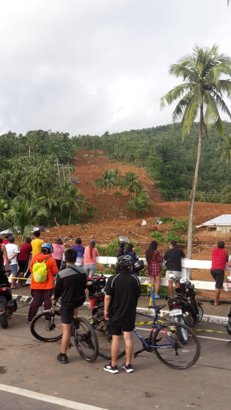 landslide in Barangay Bunga, Leyte, shot taken from a street with with cyclists and other people in the foreground