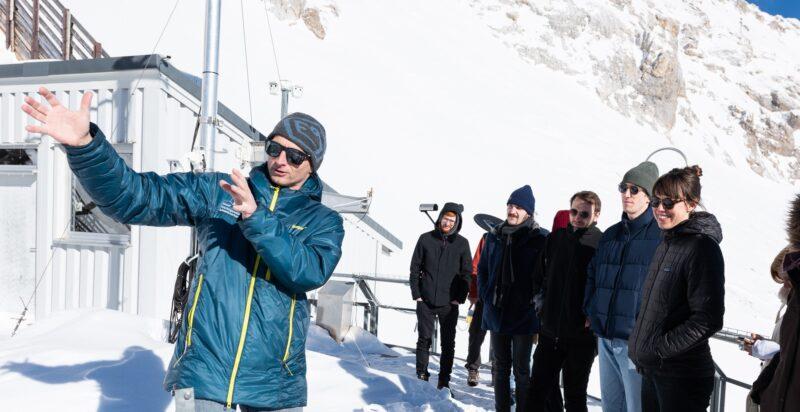 Several PhDs standing outside the Schneefernerhaus with Dr. Till Rehm with a mountain in the back