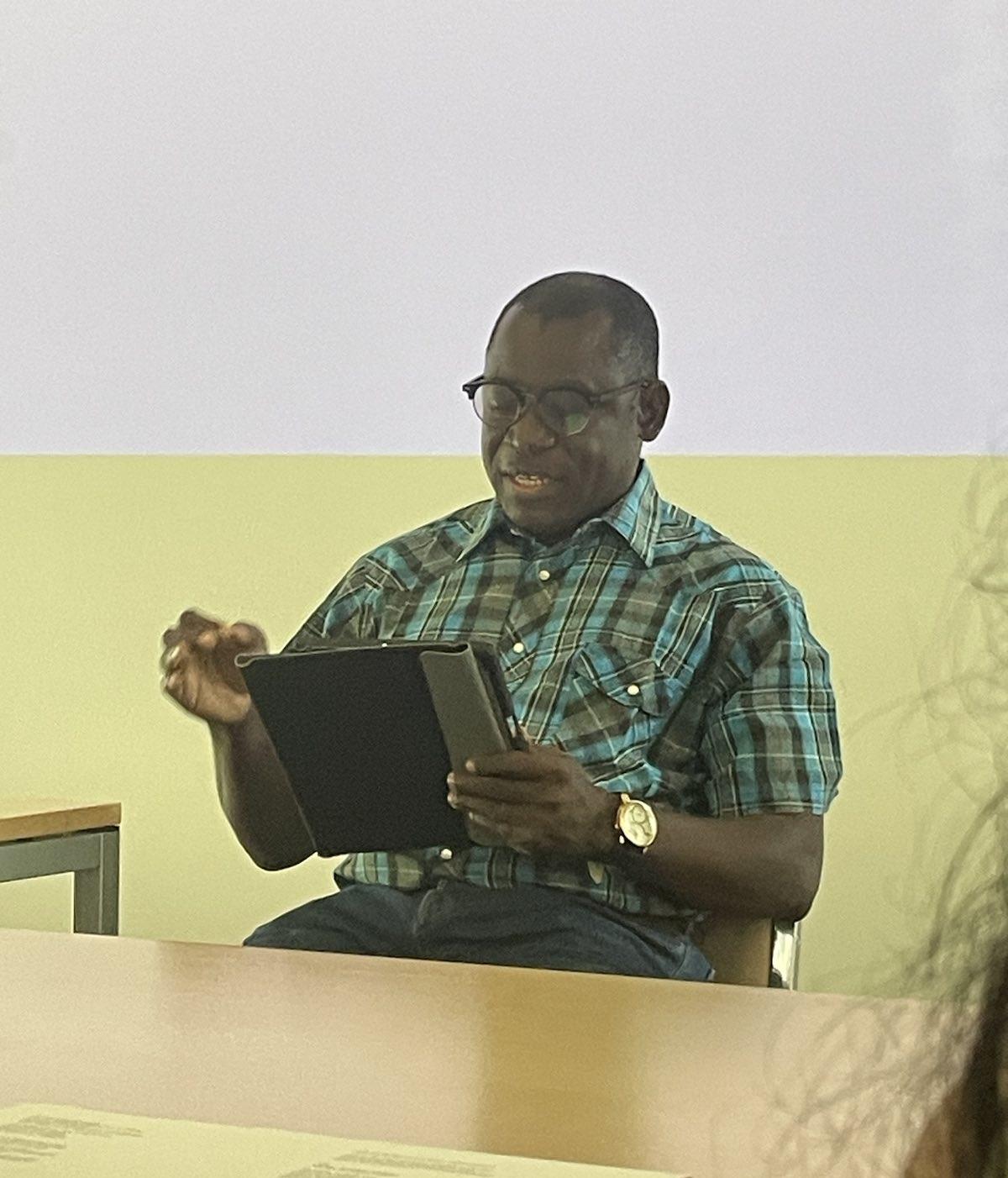 Sule E. Egya during his lecture, sitting, with a tablet in his hand